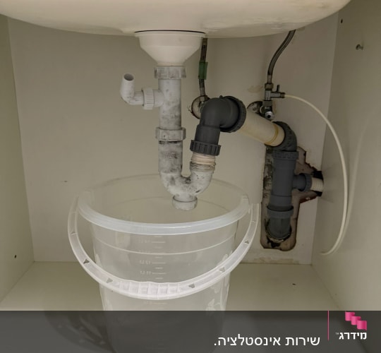 צנרת מתחת לכיור עם דלי פלסטיק שקוף